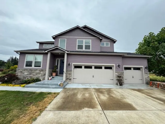 Two-story home with mauve siding, stone accents and a three-car garage