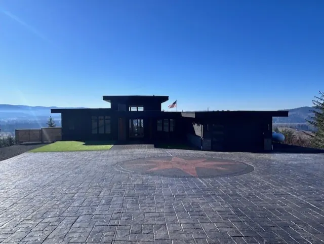 Dark contemporary home above a stamped-concrete courtyard with a compass star