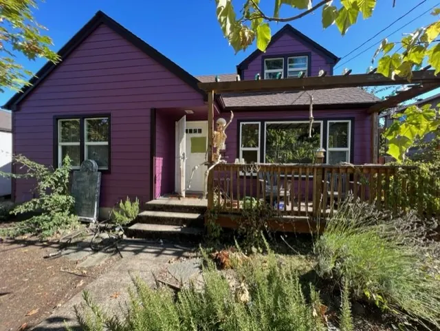 Bold purple cottage with a wooden deck and dark trim
