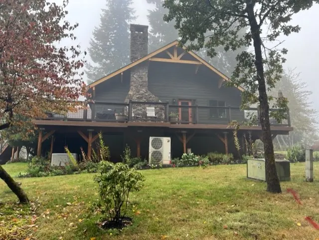 Craftsman-style home with a timber gable and stone chimney in morning fog