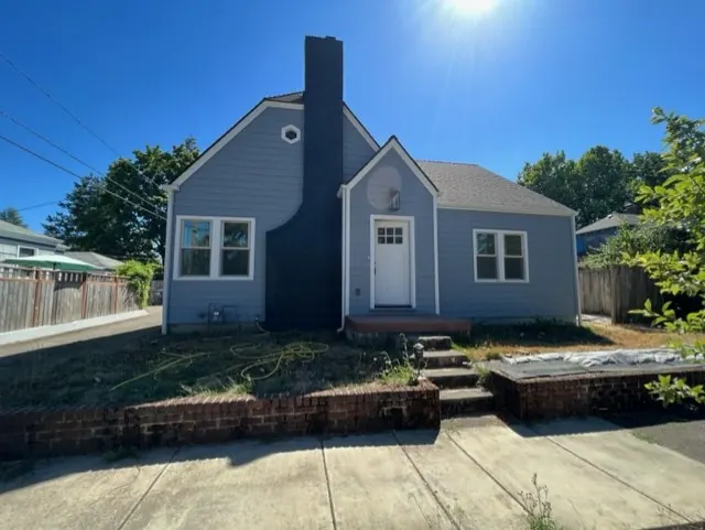Blue-gray cottage with a dark chimney and a white front door