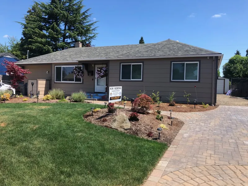 Brown ranch home with new siding, fresh landscaping and a paver driveway