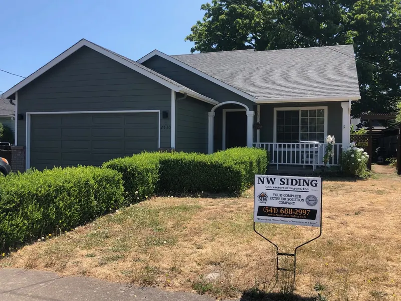 Dark green-gray home with white trim and a trimmed hedge