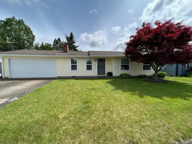 Long single-story home with cream siding and a red maple in the yard