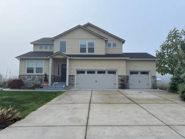 Beige two-story home with stone accents and a three-car garage