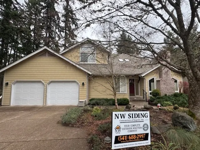 Tan home with new siding and an NW Siding yard sign